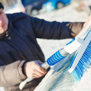 Man cleaning car from snow by doing winter hacks