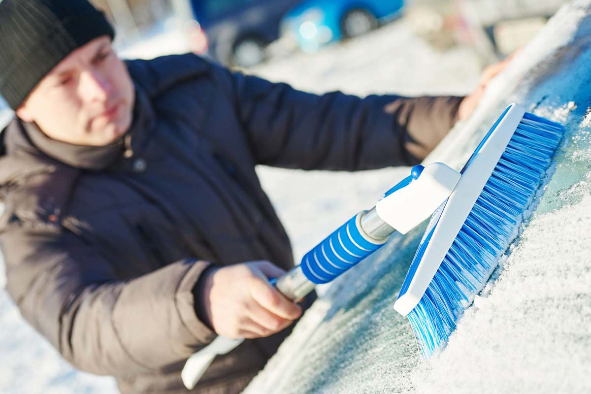 Man cleaning car from snow by doing winter hacks