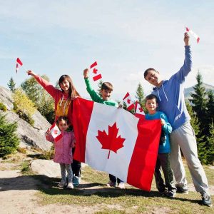 Canada Day Celebration - New Immigrants holding Big Canada Flag with Mountain Background