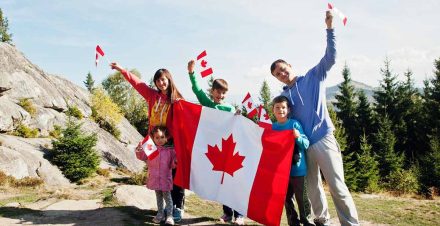 Canada Day Celebration - New Immigrants holding Big Canada Flag with Mountain Background