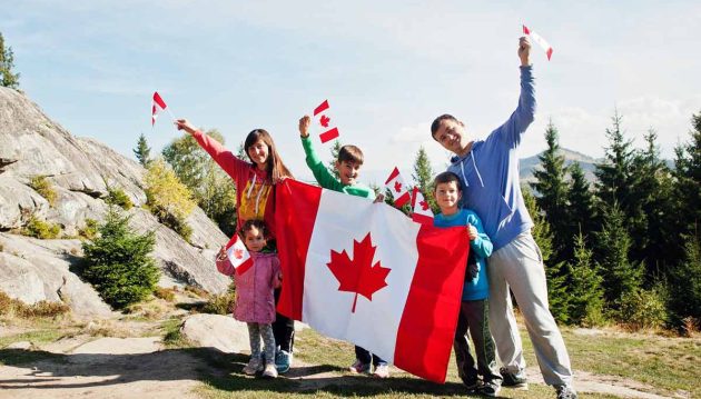 Canada Day Celebration - New Immigrants holding Big Canada Flag with Mountain Background