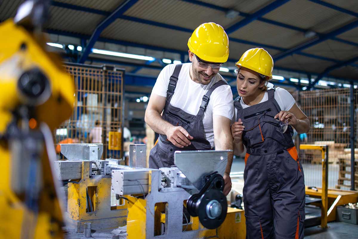 Factory workers operating industrial machine