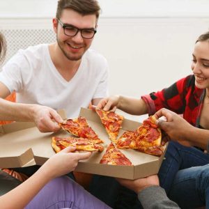 Students sharing pizza at home party