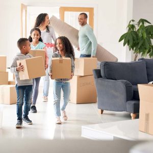 Smiling Family Carrying Boxes into New Home on Moving Day