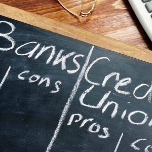 Banks vs. Credit Unions pros and cons written on a blackboard