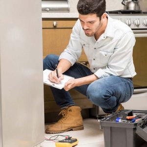 Handyman repairing refrigerator in kitchen