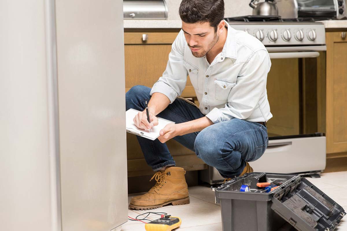 Handyman repairing refrigerator in kitchen