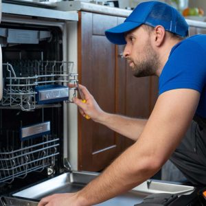 Technician repairing dishwasher in kitchen