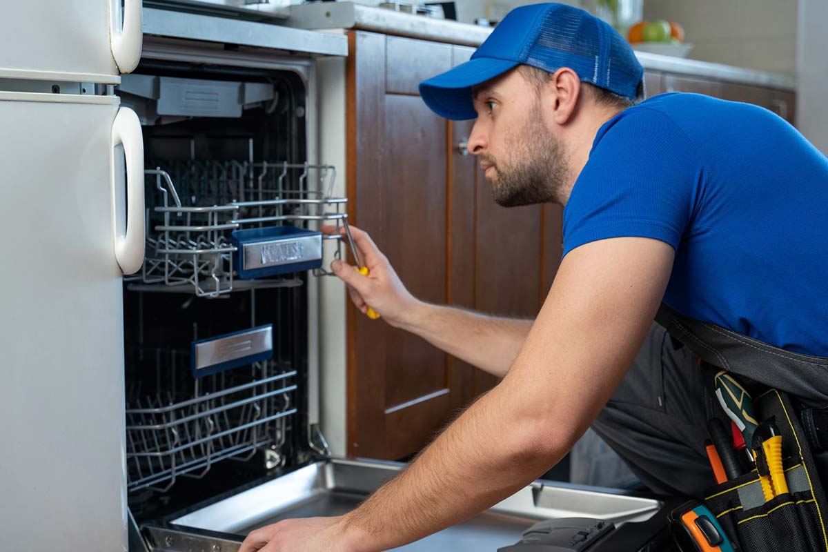 Technician repairing dishwasher in kitchen