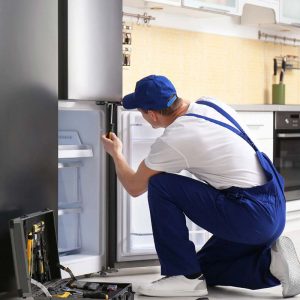 Technician repairing refrigerator in kitchen