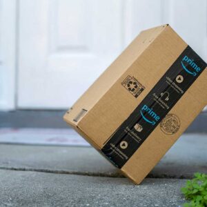 Box with Amazon logo in front of house door. Ordered online as Christmas or birthday gifts